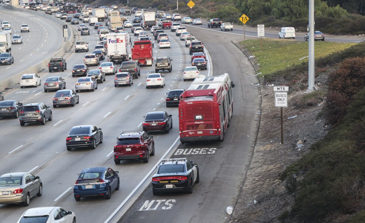 From Market Street looking northbound on Interstate 805, a bus rides the shoulder with a CHP escor.