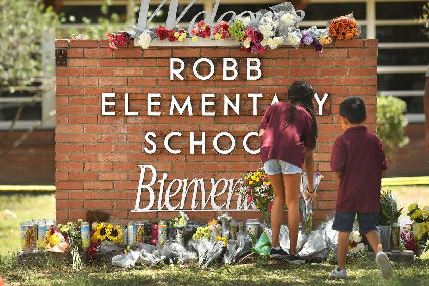 Uvalde, Texas May 25, 2022-Family members who lost a sibling place flowers outside Robb Elementary School in Uvalde, Texas Wednesday. (The family did notice any information other than they lost a child) (Wally Skalij/Los Angeles Times)