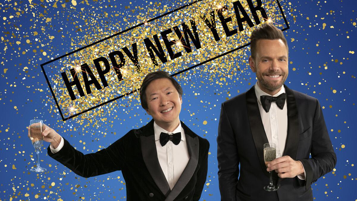 Ken Jeong and Joel McHale in tuxedos under a banner reading "Happy New Year."