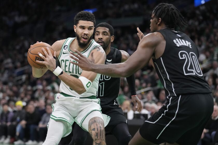 Jayson Tatum, de los Celtics de Boston, intenta pasar entre Day'ron Sharpe y Kyrie Irving, de los Nets de Brooklyn, durante el partido del miércoles 1 de febrero de 2023 (AP Foto/Charles Krupa)