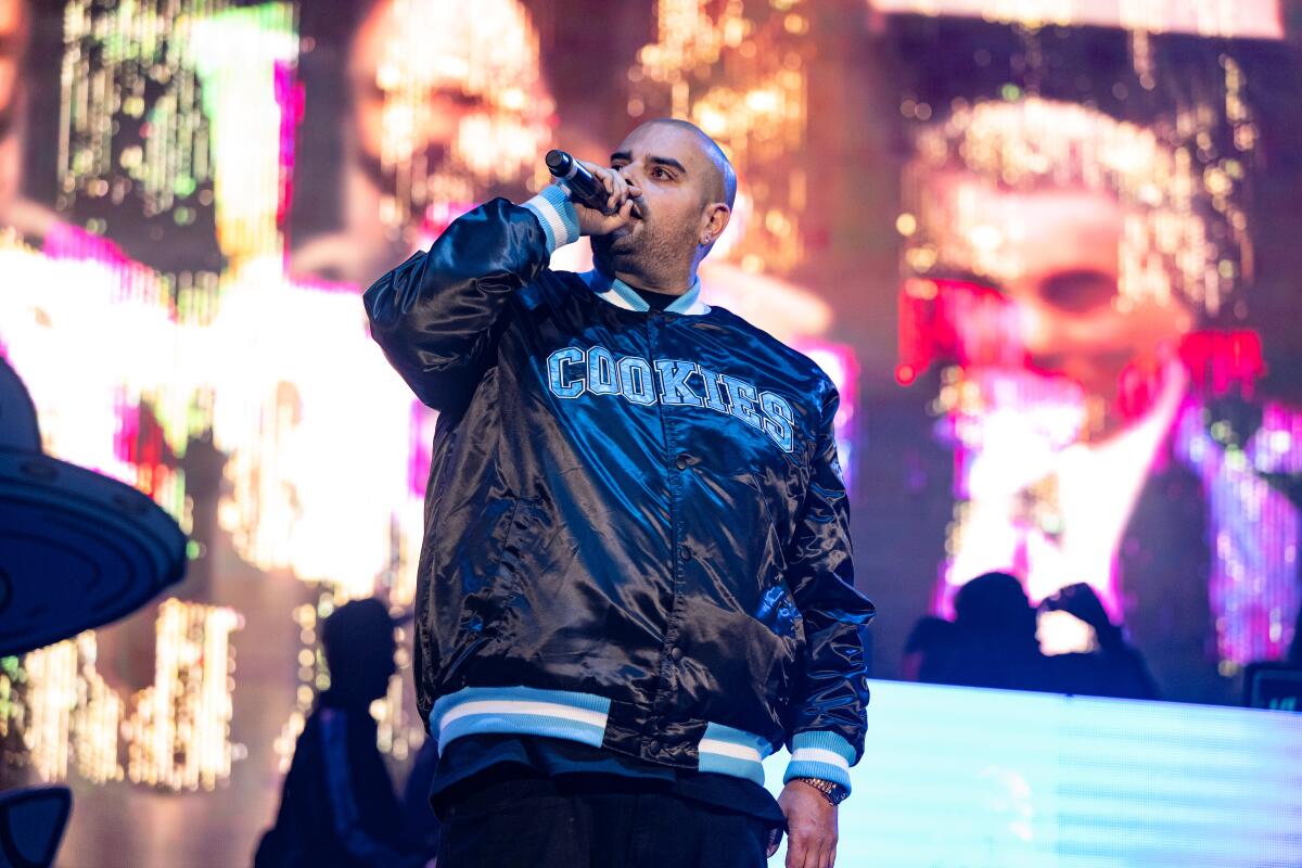 A rapper wearing a jacket with the word "Cookies" performs on a stage.
