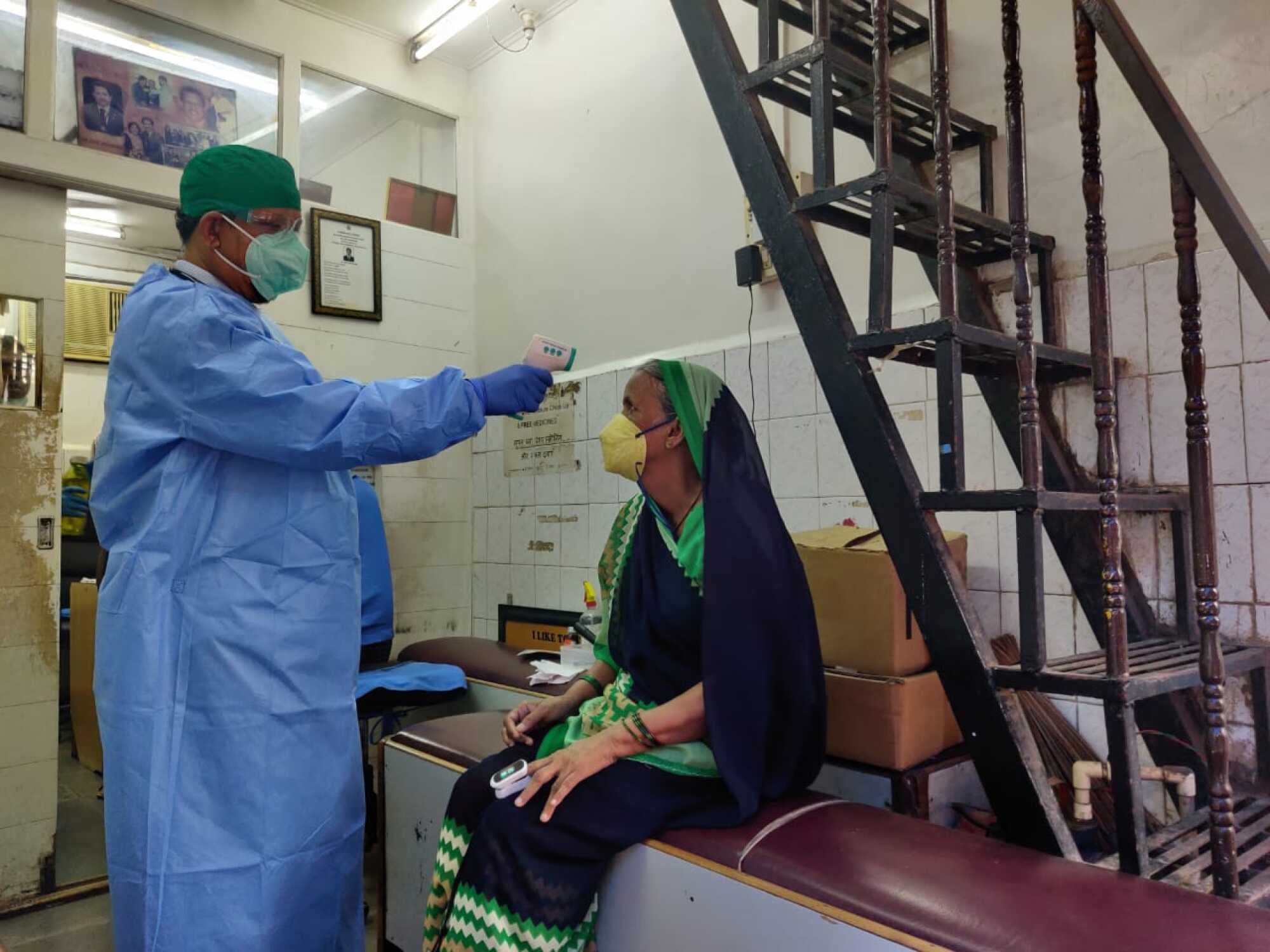 Physician Anil Pachanekar examines Lilavati, a patient, in his Dharavi clinic.