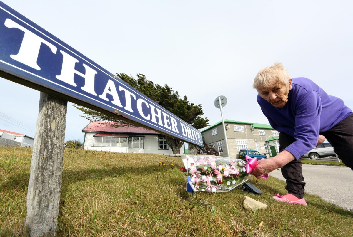 A woman in Port Stanley, Falkland Islands, places flowers to honor the memory of former British Prime Minister Margaret Thatcher.