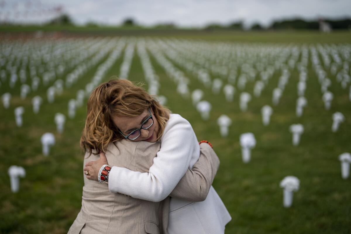 Two women embrace on a grass lawn