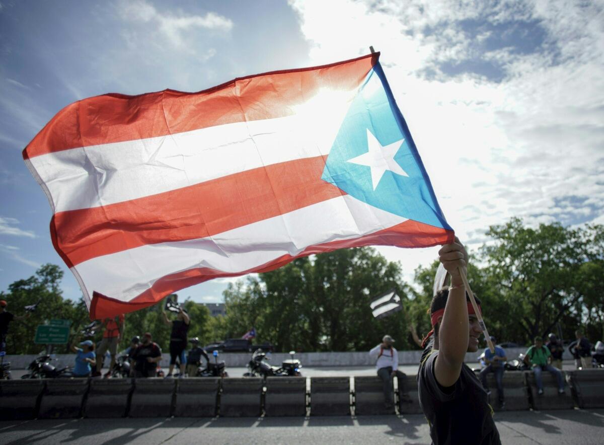 A protester waves the Puerto Rican flag in San Juan during protests demanding the resignation of Gov. Ricardo Rossello.