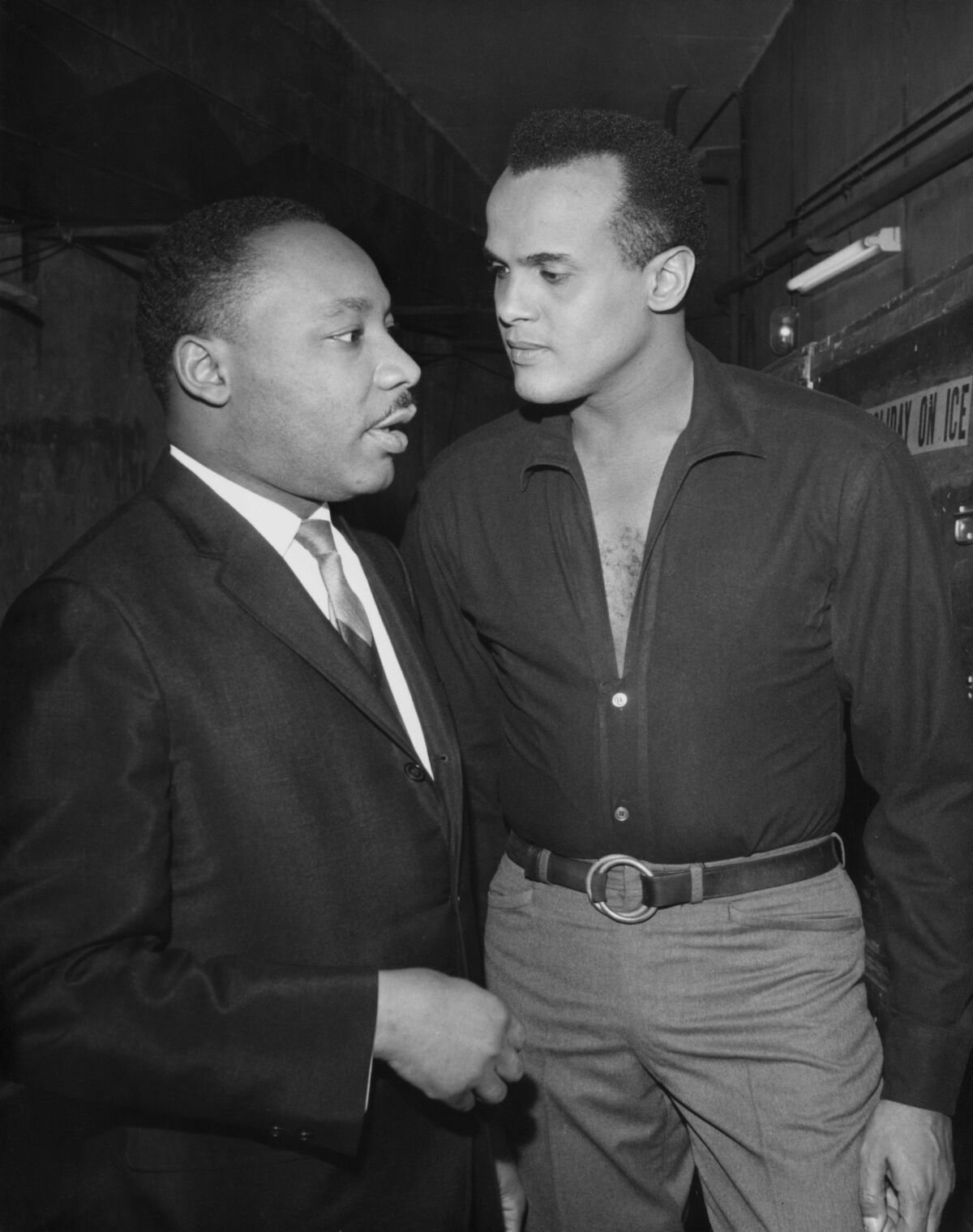Solda Martin Luther King Jr. ve Harry Belafonte'nin birlikte konuştuğu siyah beyaz dikey çerçeve