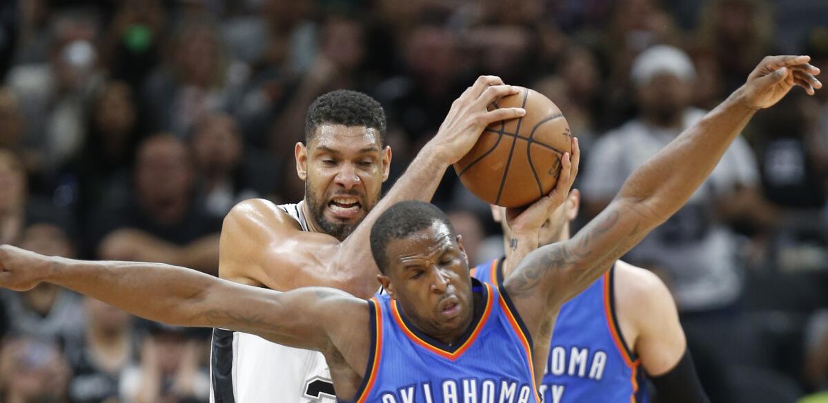 Spurs forward Tim Duncan grabs a rebound in front of Oklahoma City guard Dion Waiters during a game on April 12.