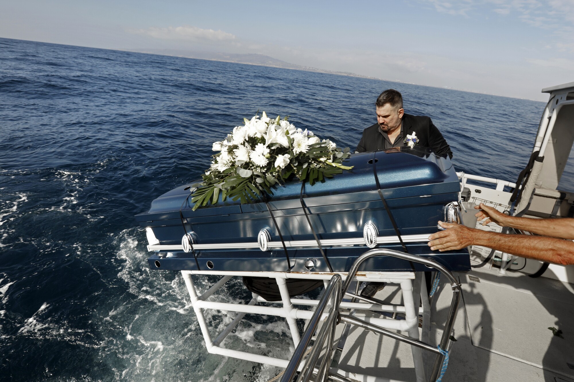 El director de la funeraria Ken McKenzie baja el ataúd de una amiga, Joyce Faye Gordan, al mar.