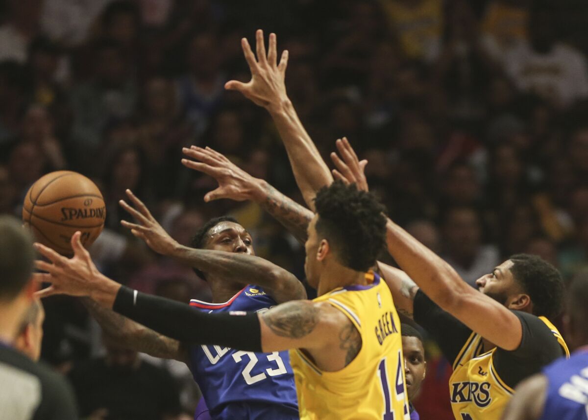 Clippers guard Lou Williams looks to pass after he's trapped by Lakers defenders.