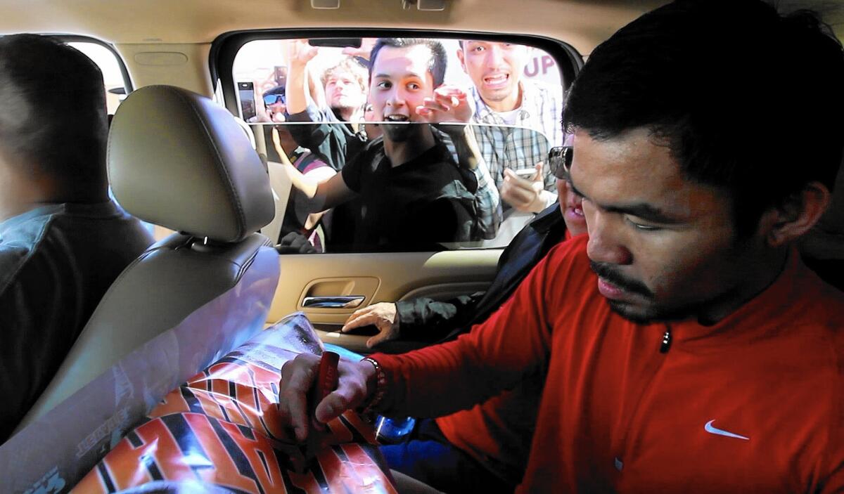 Manny Pacquiao signs a poster for a fan as he leaves Wild Card Boxing Gym in Hollywood on April 27, before heading to Las Vegas.