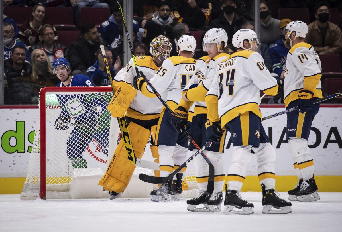 Vancouver Canucks' Conor Garland, back left, looks on as Nashville Predators goalie Juuse Saros, Alexandre Carrier, Mikael Granlund, Tanner Jeannot and Mattias Ekholm, from left, celebrate the team's win in an NHL hockey game Friday, Nov. 5, 2021, in Vancouver, British Columbia. (Darryl Dyck/The Canadian Press via AP)