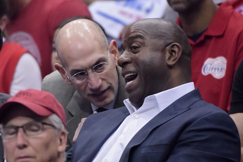 NBA Commissioner Adam Silver, left, talks with Magic Johnson as they watch the Los Angeles Clippers play the Oklahoma City Thunder in the first half of Game 4 of the Western Conference semifinal NBA basketball playoff series, Sunday, May 11, 2014, in Los Angeles.