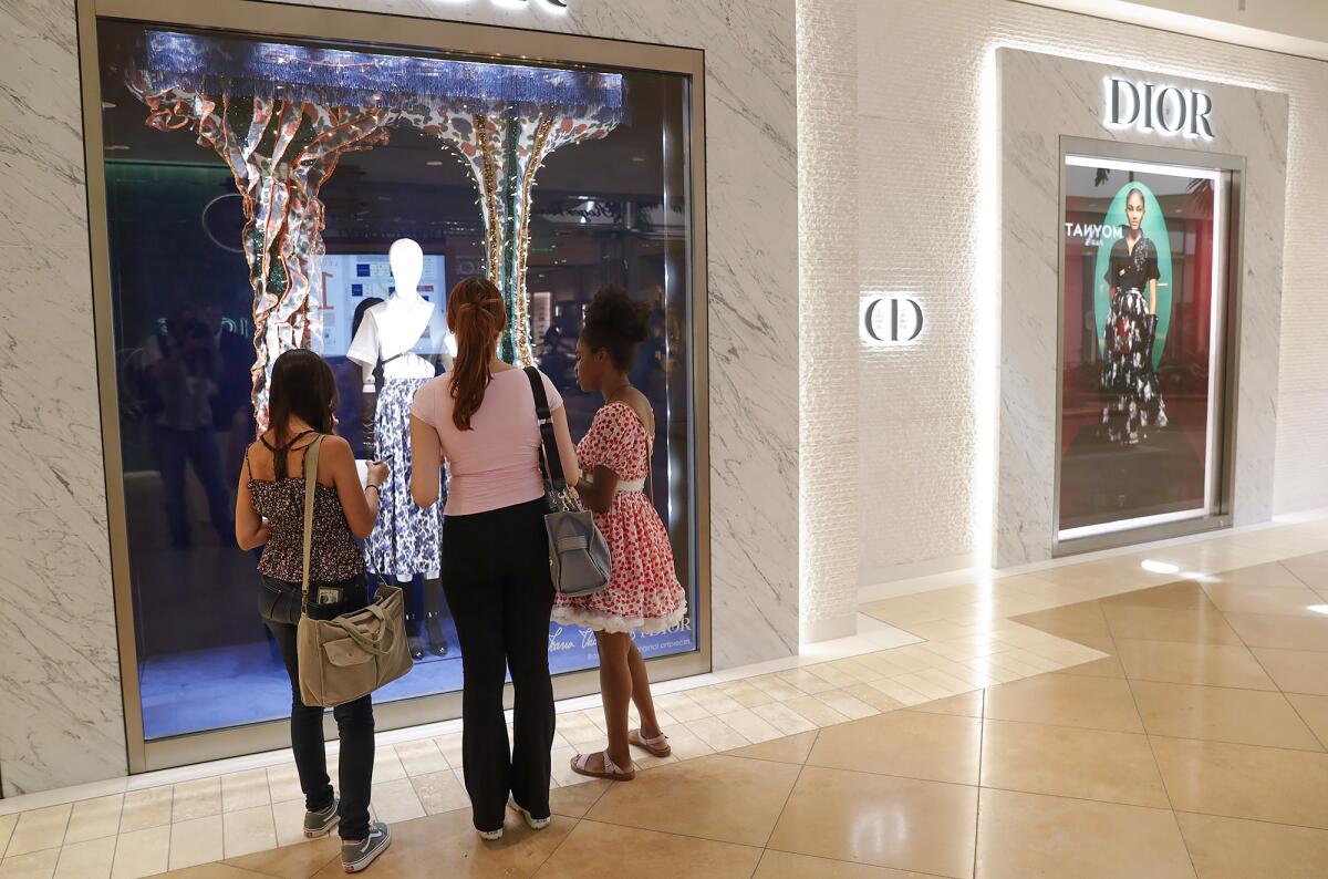 Velinda Quintana, Lizbeth Delgado, Rebecca Lee, from left, take notes on the Dior storefront display at South Coast Plaza.