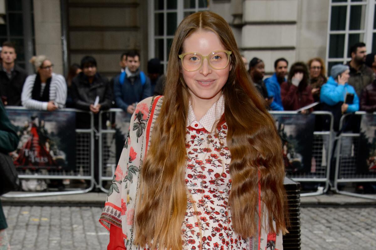 Jessie Cave poses in glasses and a red-patterned shirt.