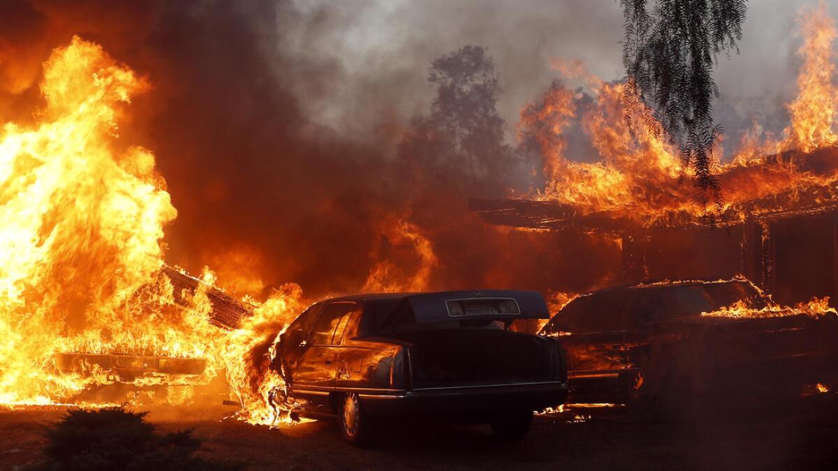 A home and cars in the path of the Creek fire are engulfed in flames.
