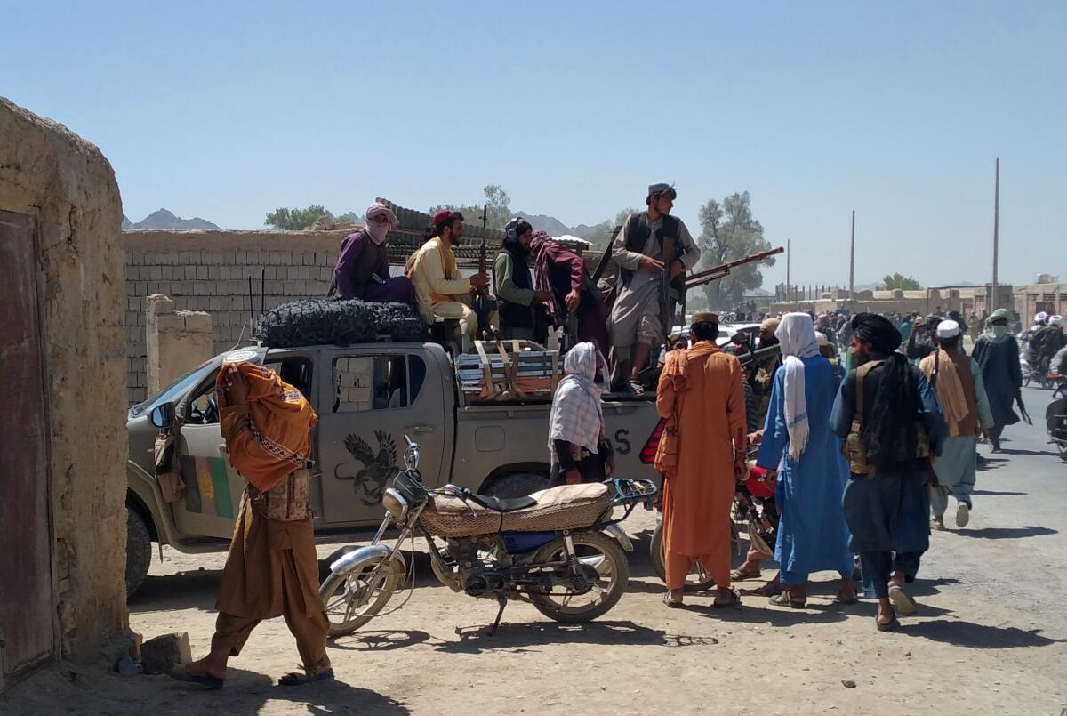People stand next to a loaded pickup truck on a dusty street 