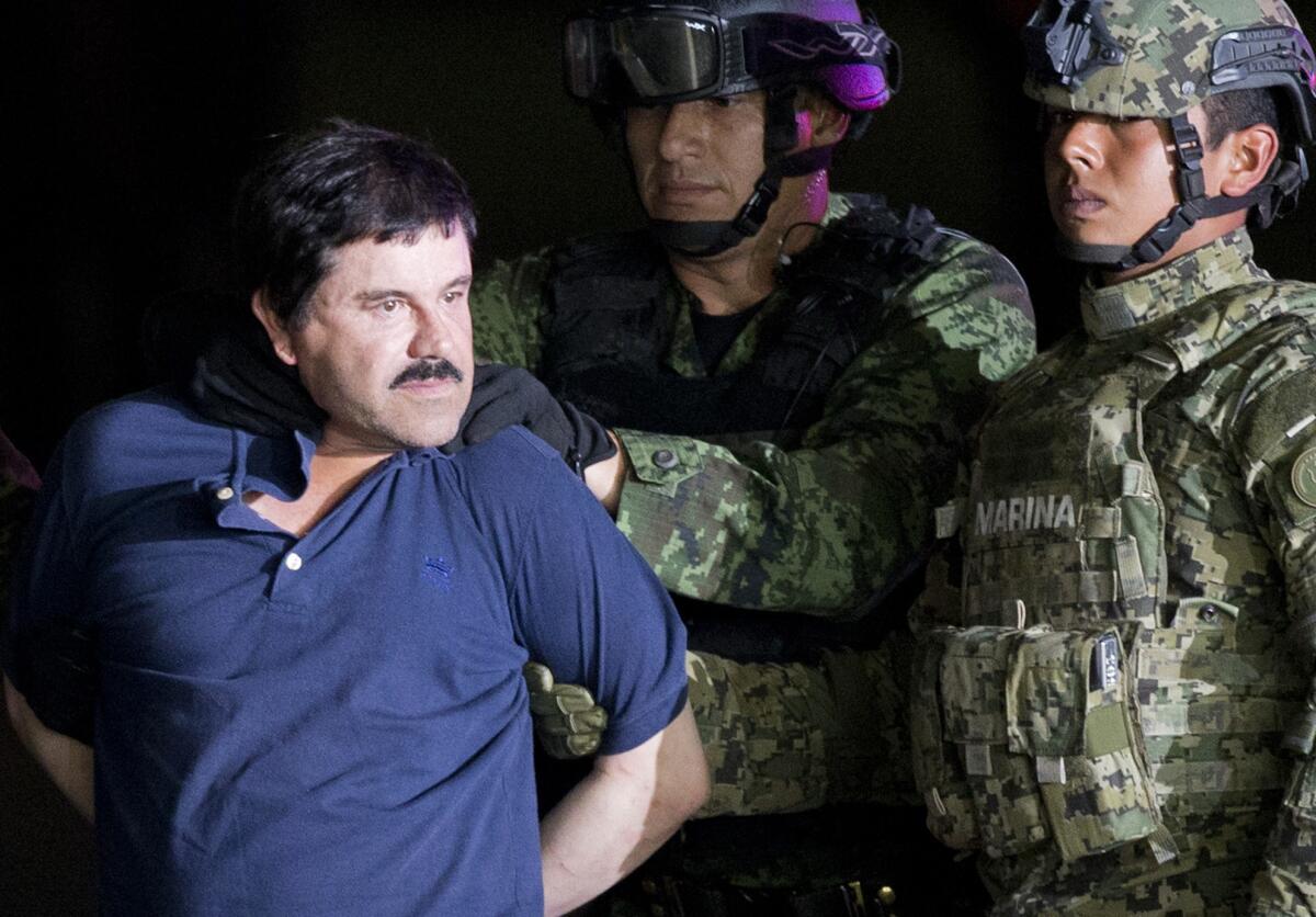 Joaquín "El Chapo" Guzmán es obligado a mirar a la prensa mientras es escoltado a un helicóptero por soldados mexicanos en un hangar federal en Ciudad de México, el viernes 8 de enero de 2016.
