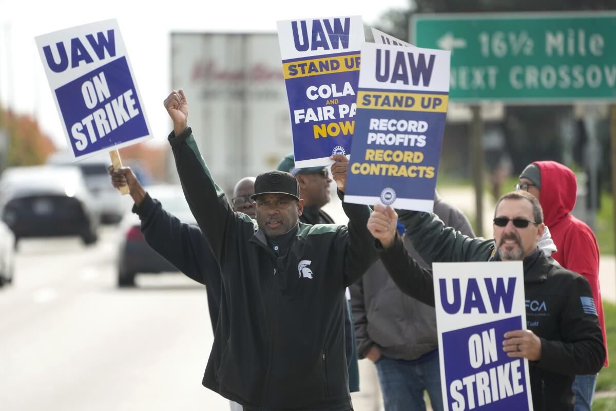 Autoworkers on a picket line hold strike signs