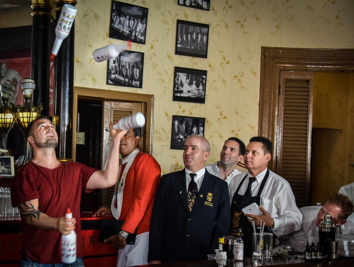 Argentine bartender Christian Delpech, left, who lives and works in Las Vegas, plays with bottles of rum in July at the Floridita bar in Havana.