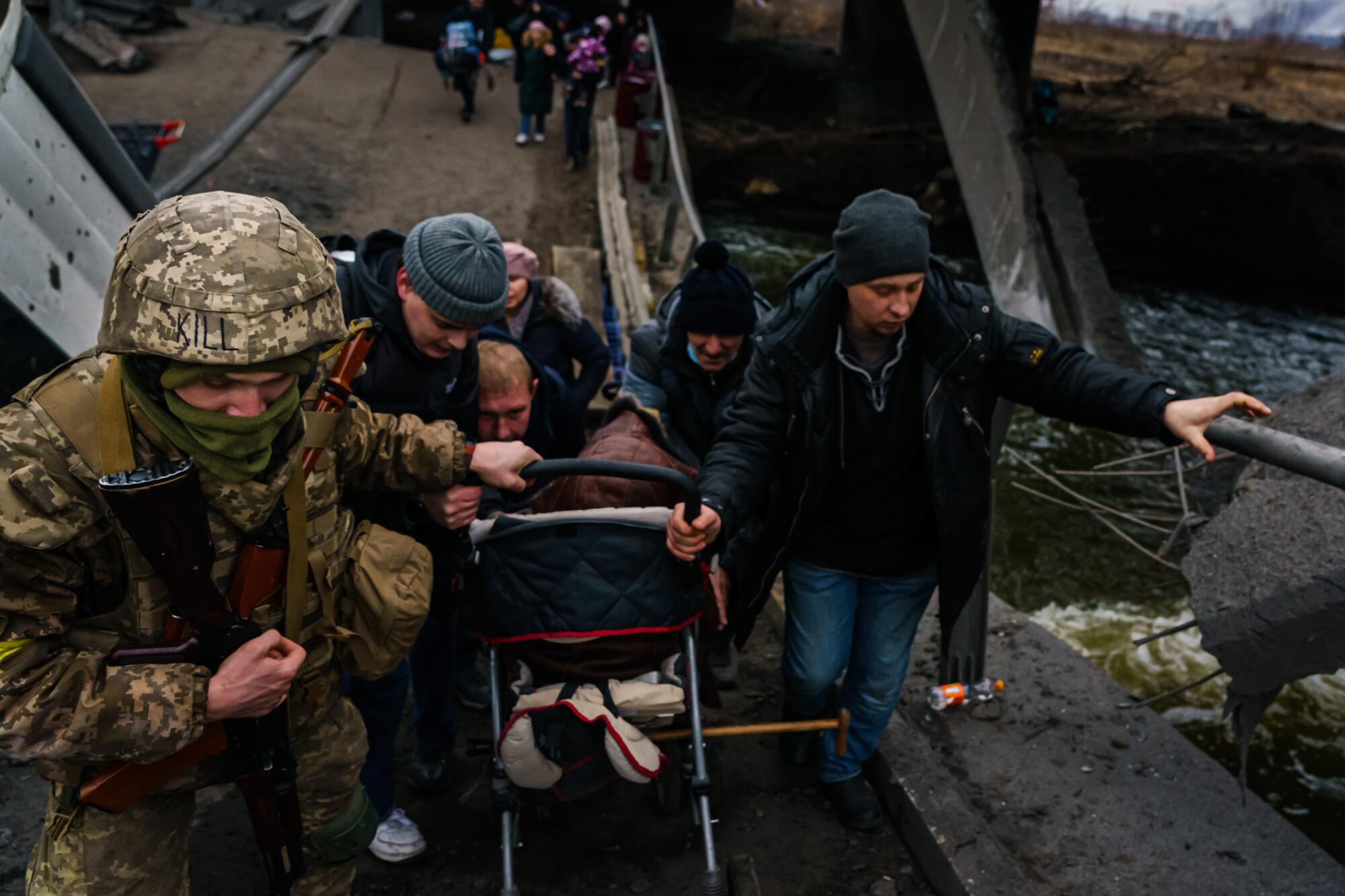 Soldiers help civilians cross the Irpin river and evacuate as Russian forces advance