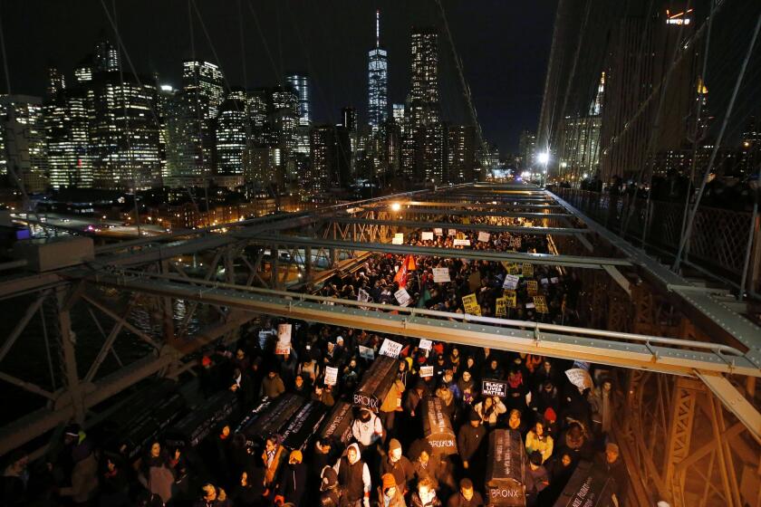 Protesters carry a collection of mock coffins bearing the names of victims of fatal police encounters as they cross the eastbound traffic lanes of the Brooklyn Bridge.