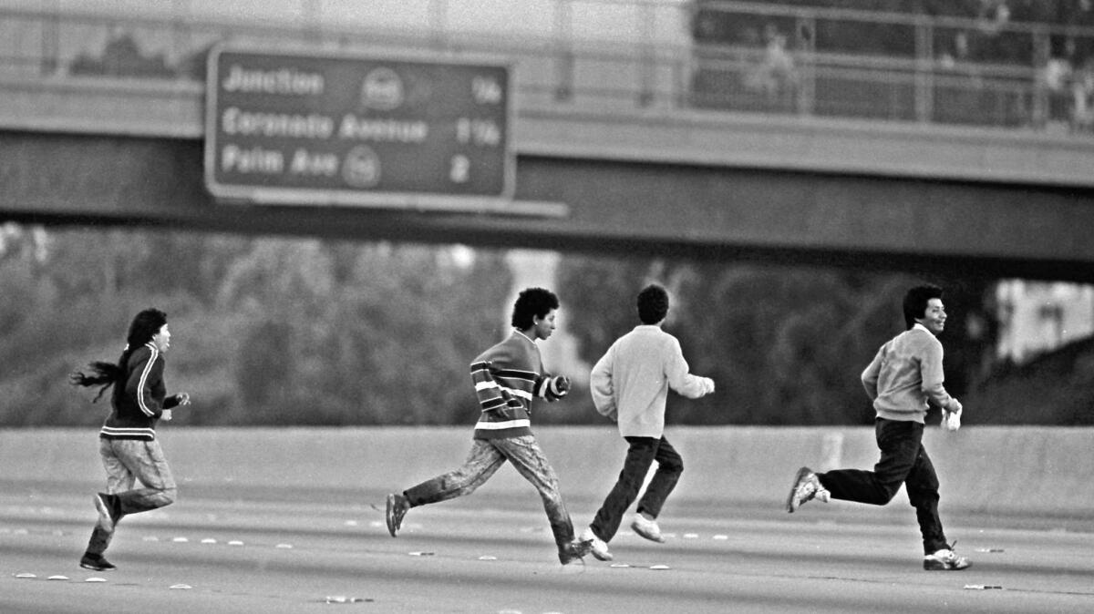 With their shoes and pant legs still wet after walking in the nearby Tijuana River valley, a group of young people sprint across I-5.