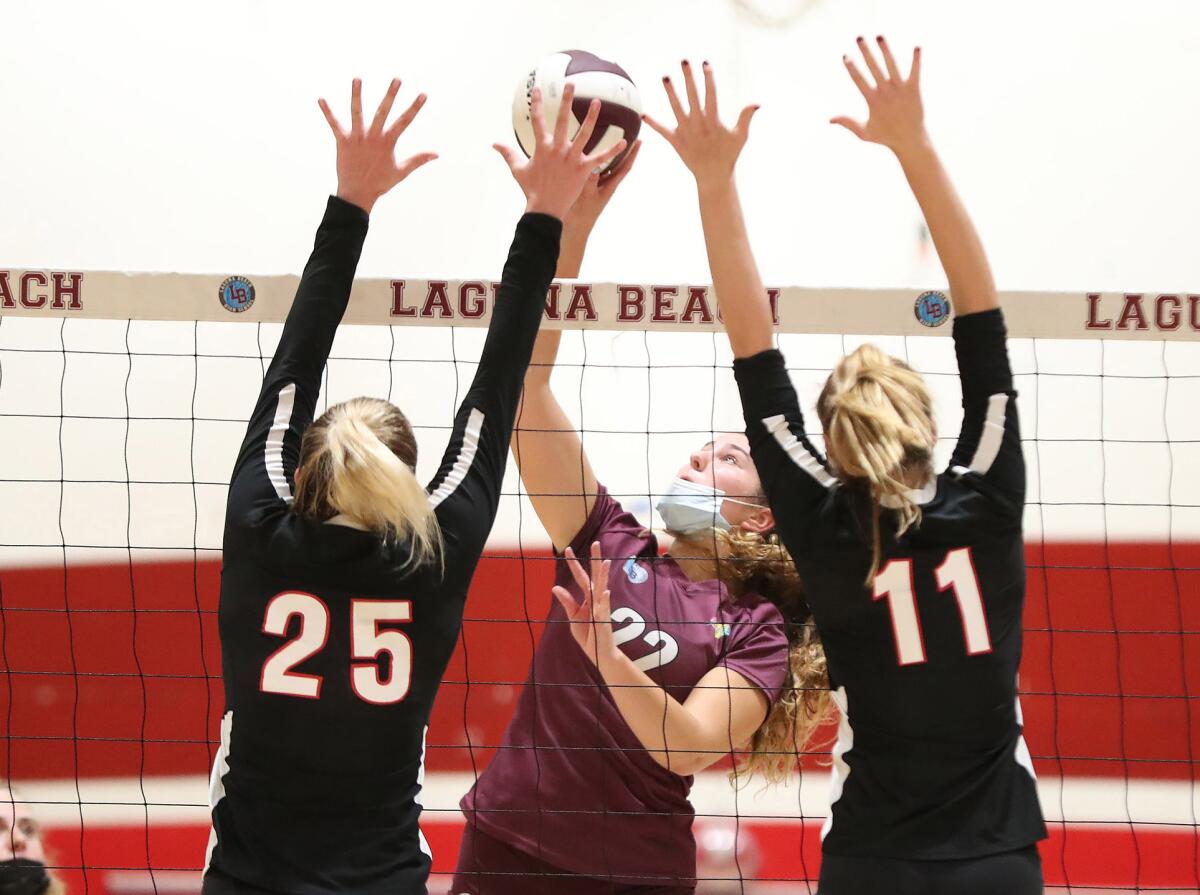 Laguna's Sara Johnson (22) goes up against Flintridge Sacred Heart blockers Nikki Garriola (25) and Piper Scherbert (11).