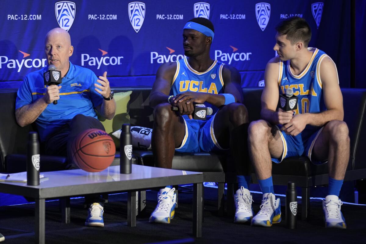 UCLA coach Mick Cronin speaks beside players Adem Bona, center, and Lazar Stefanovic.
