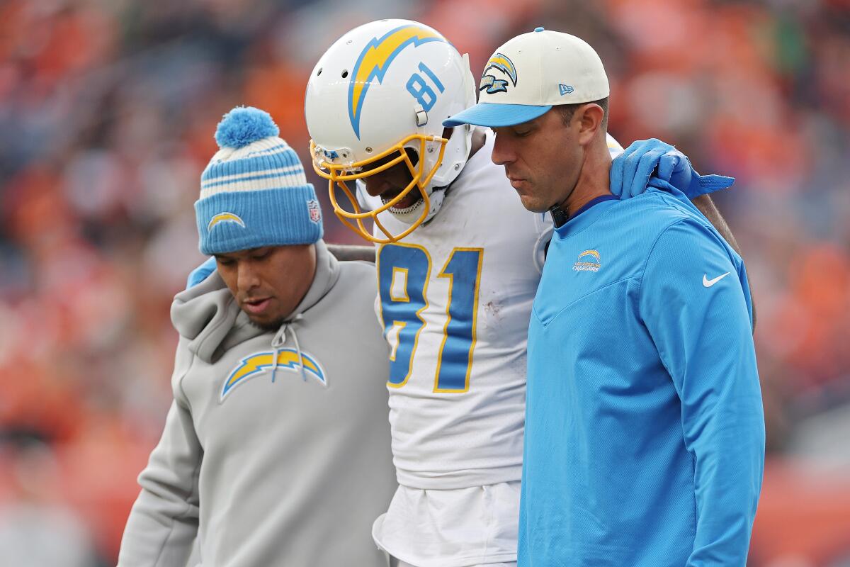 Trainers assist the Chargers' Mike Williams off the field after the receiver hurt his back against Denver.