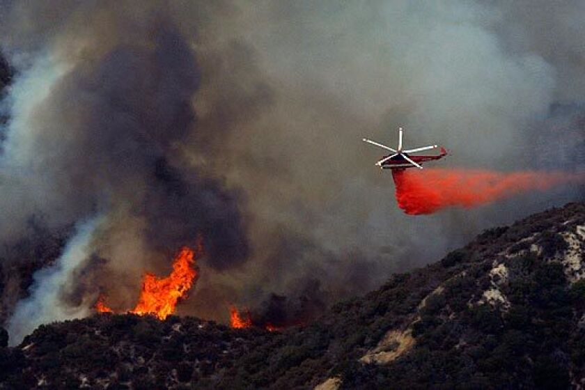 A helicopter drops fire retardant on a part of the Station fire burning close to homes in Tujunga's Blanchard Canyon.
