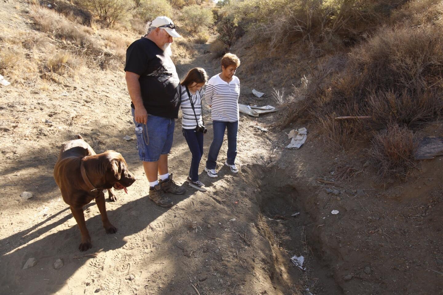 Rocky Ramos, 60, walks with his wife, Isabel, and granddaughter Sophia Salazar, 9, and their dog Buddy at the Palmdale site of the shallow grave where Buddy sniffed out a human skull that turned out to belong to missing Fox executive Gavin Smith.