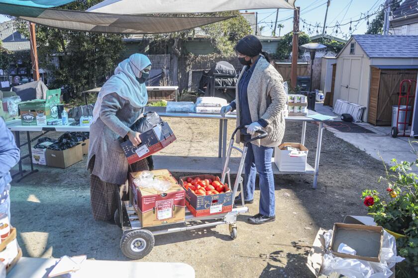 San Diego, CA - January 26: Katherine Bom (right), executive director of RefugeeNet, helps with food and supplies for refugee Mouna Mohamed (left) during a food drive at St. Lukes Church on Thursday, Jan. 26, 2023 in San Diego, CA. (Eduardo Contreras / The San Diego Union-Tribune)