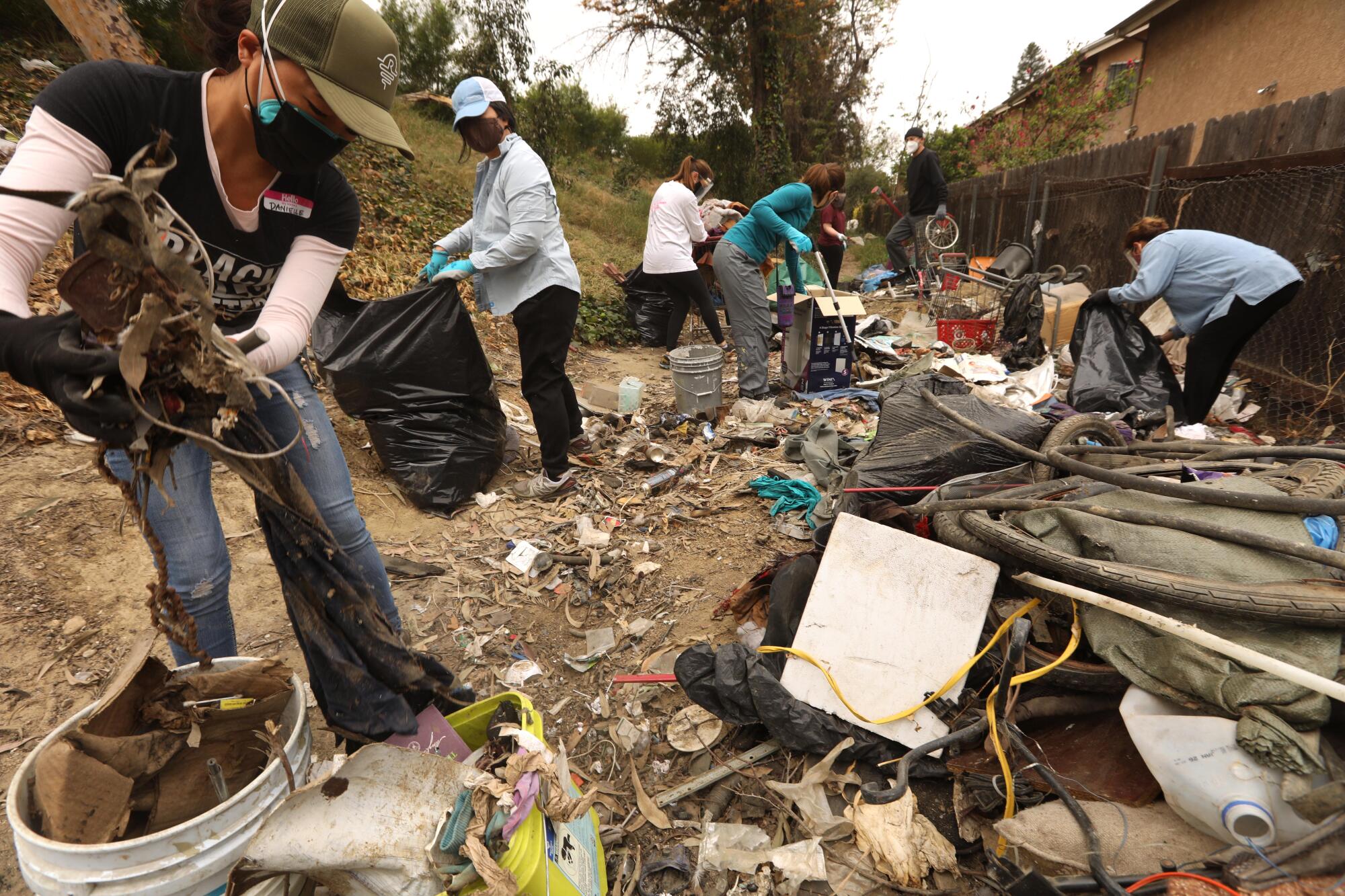 People clean up debris behind a building