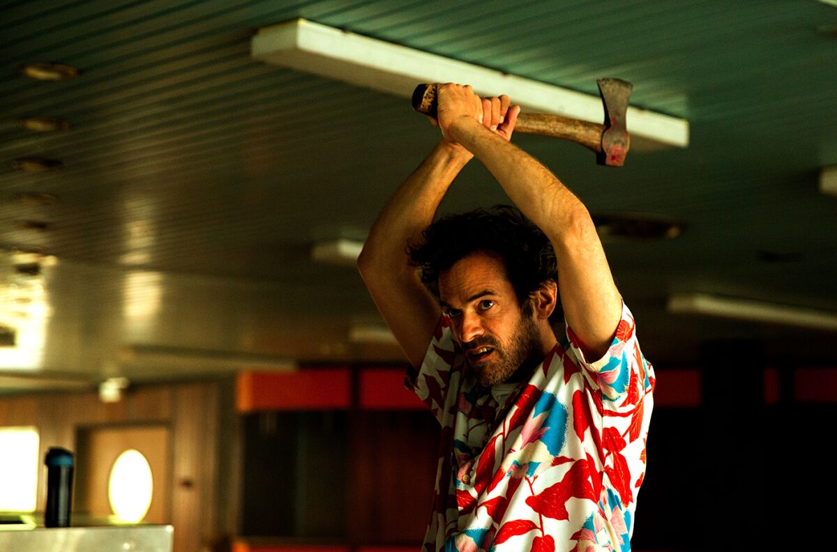 A man in a pattern-print shirt wields an axe