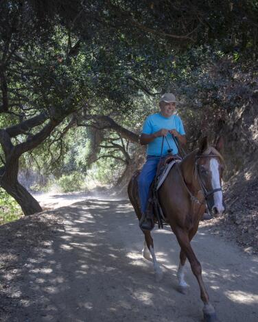 A man enjoying riding a horse on this shady equestrian trail in Griffith Park.