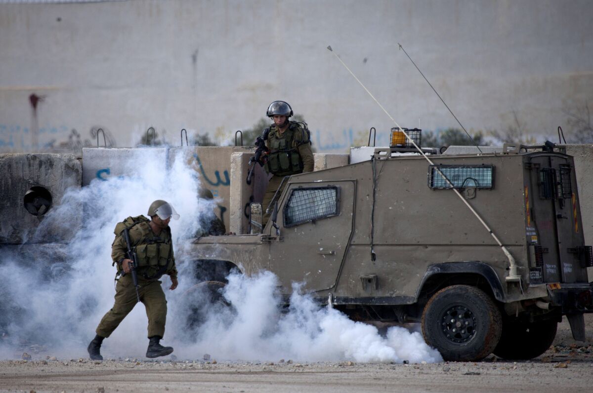 Israeli soldiers run from tear gas during clashes outside the Ofer military prison near the West Bank city of Ramallah on Nov. 18.