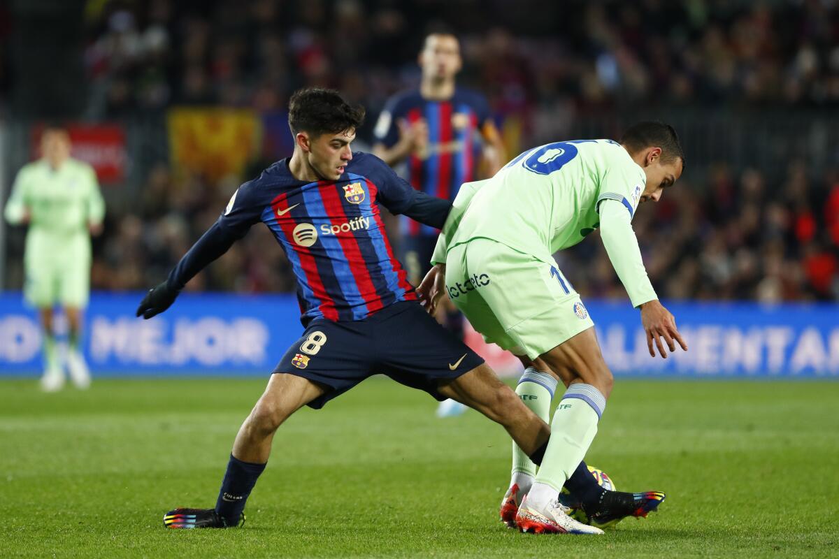 Pedri (izquierda) del Barcelona pugna el balón con Ángel Algobia del Getafe en el partido de la Liga española