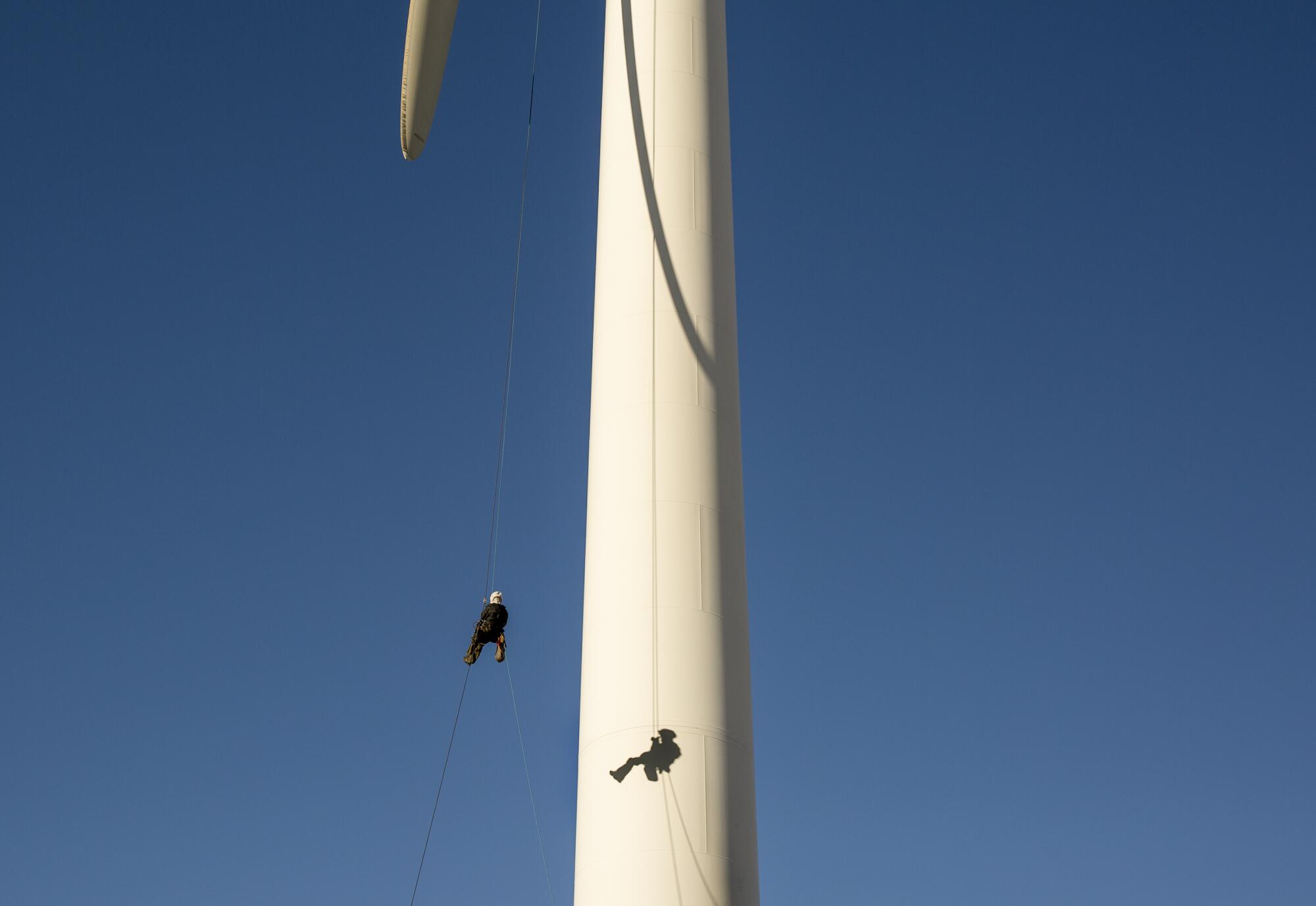 A person hangs from a wind turbine.