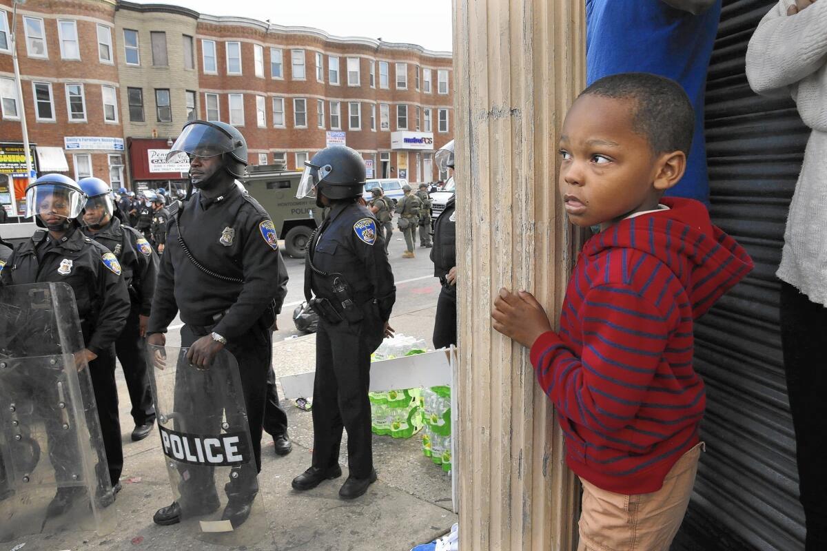 Jayden Thorpe, 5, and his mother observe what's happening Tuesday in the Baltimore neighborhood where a CVS was looted the night before.
