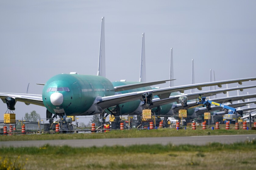 FILE - A line of Boeing 777X jets are parked nose to tail on an unused runway at Paine Field, near Boeing's massive production facility, Friday, April 23, 2021, in Everett, Wash. After a couple dismal years, Boeing is getting more orders and delivering more airline planes. The company said Tuesday, Jan. 11, 2022, that it delivered 38 commercial planes in December and 340 for all of 2021. (AP Photo/Elaine Thompson, File)