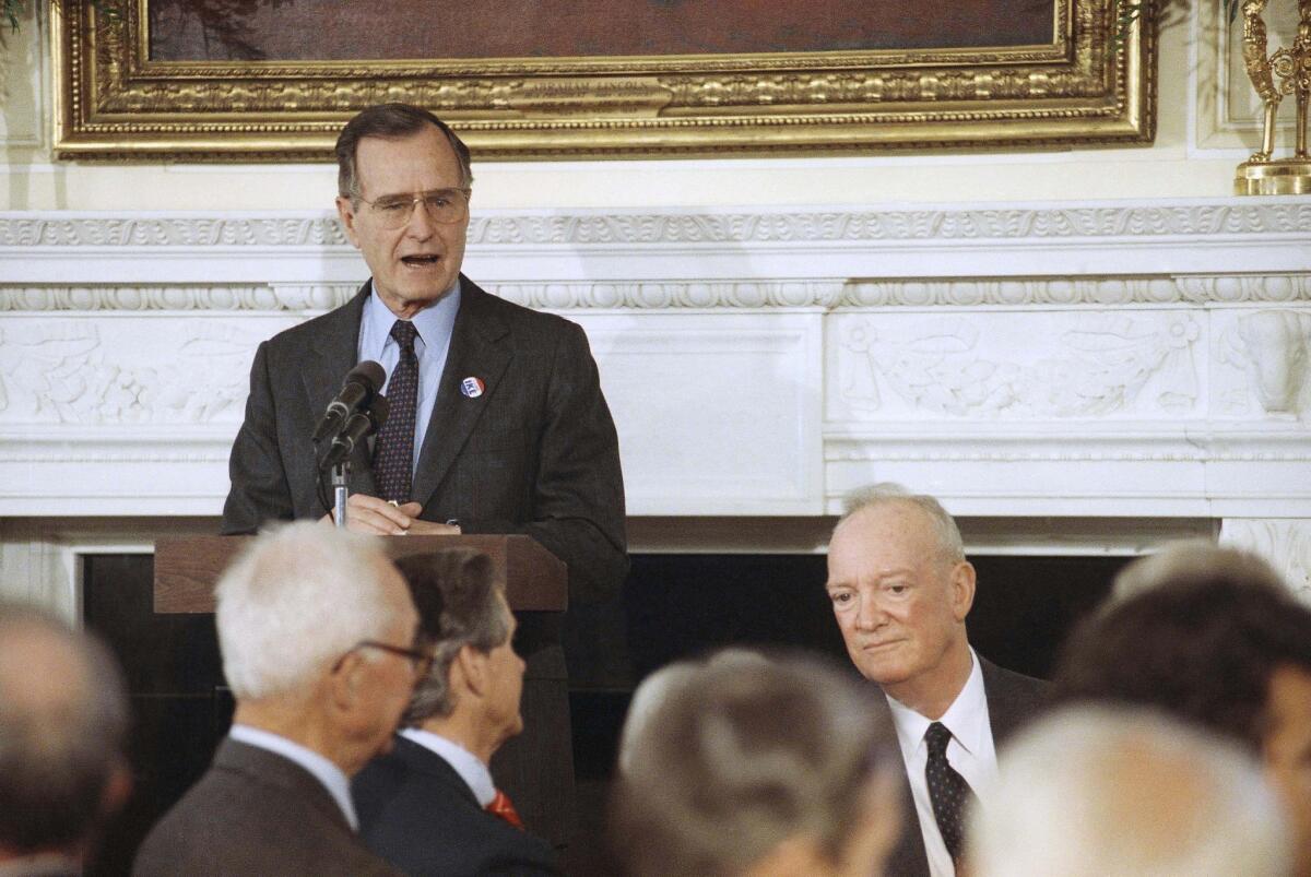 In this 1990 file photo, U.S. President George H. W. Bush, standing, addresses a White House luncheon commemorating former President Dwight. D. Eisenhower's 100th birthday. At right is John S.D. Eisenhower, the former president's son. John S.D. Eisenhower, the son of a five-star general...