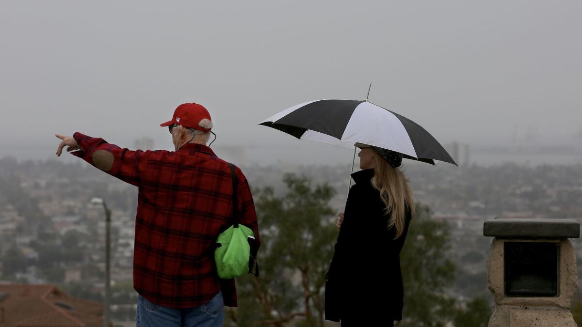 Norbert Nagel from Denver and his sister Susan Gobbel from Riverside take in the view in Signal Hill as rainy weather moves into the area Tuesday afternoon.
