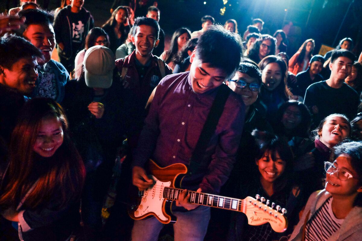 A man plays the guitar amid a crowd of people.