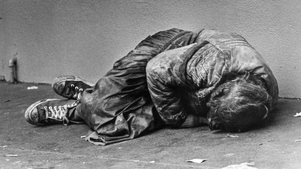 Nov. 21, 1985: A sleeping man pulls himself into fetal position for extra warmth before dawn on cold sidewalk on Hill Street in downtown Los Angeles.