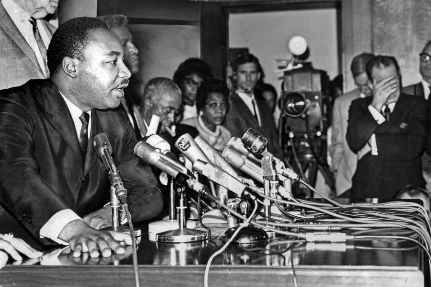 Aug. 19, 1965: Martin Luther King Jr. answers questions during a news conference at Los Angeles City Hall. Mayor Samuel W. Yorty, right, listens with hands over his eyes. Yorty later criticized King's suggestion that Police Chief William H. Parker resign following LAPD actions during the 1965 riots in Los Angeles. This photo was published in the Aug. 20, 1965, LA Times.