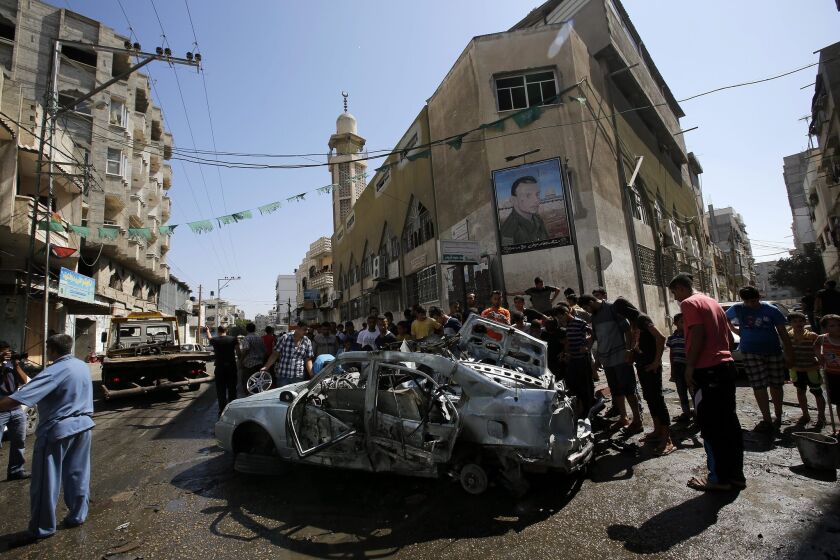 Palestinians inspect a destroyed car after Israeli airstrikes in Gaza City on Aug. 25.