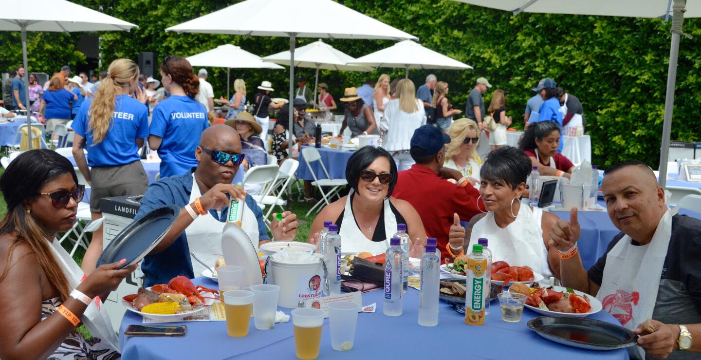 Joi Grimmett, Gary and Ghia Cunningham, Lisa Ramirez and Edward Saucerman, from left, of the Titan Group dig into their lobster meals during Lobsterfest on Sunday at the Newport Beach Civic Center.