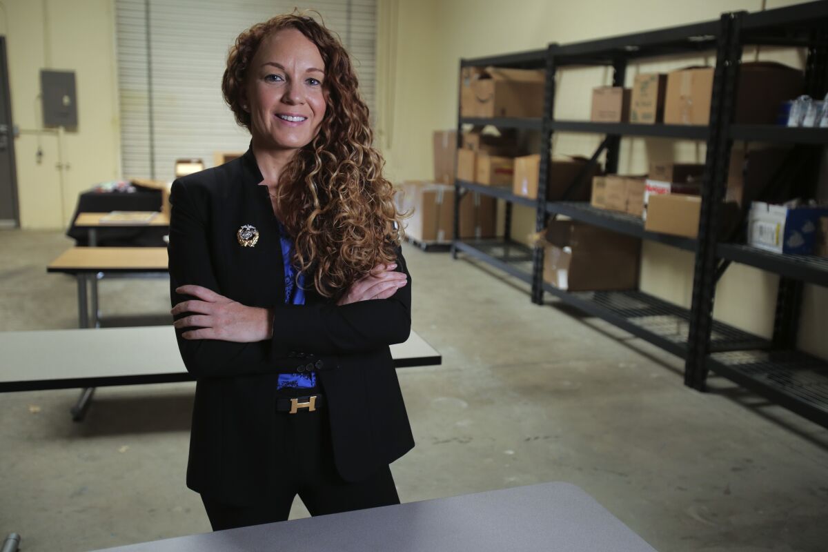 Jodie Grenier, standing with arms crossed and smiling at the camera, inside a warehouse in Vista