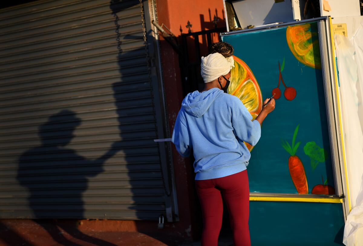 Artist Fawlene Copeland paints a donated refrigerator outside Revolutionario North African Tacos.