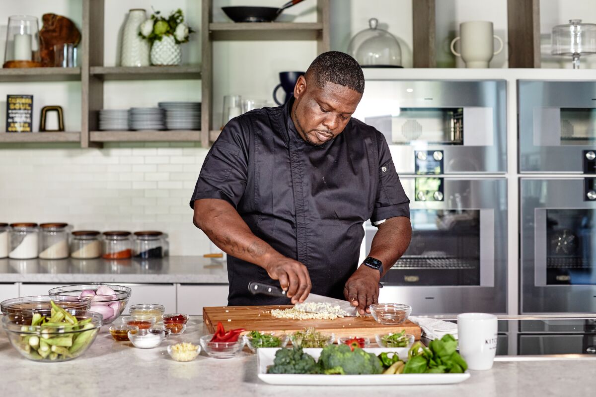 A man in a kitchen dices vegetables